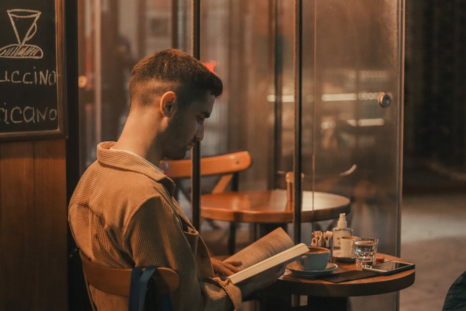 man in minimalist outfit reading book in cafe