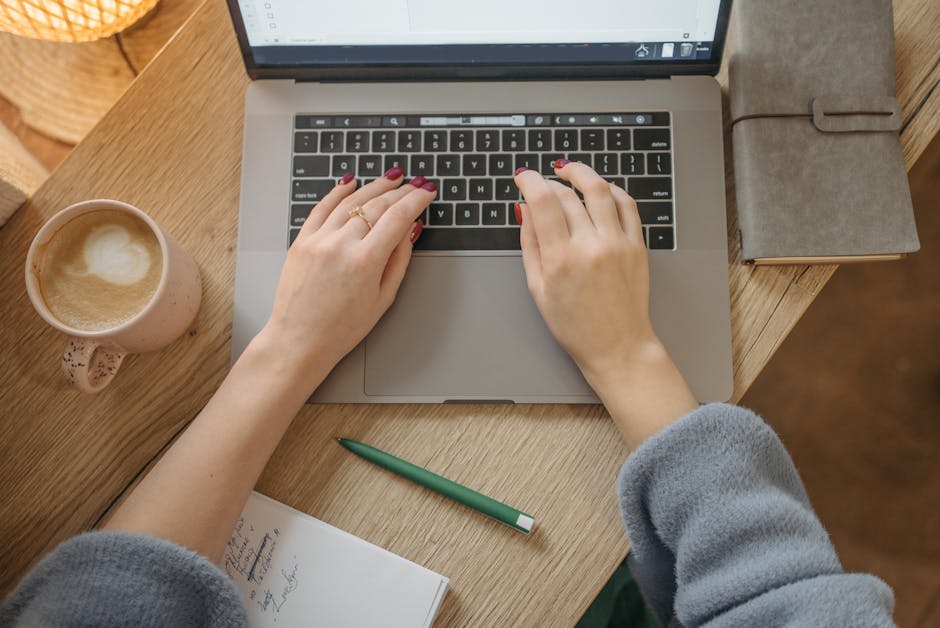 person writing on laptop with coffee