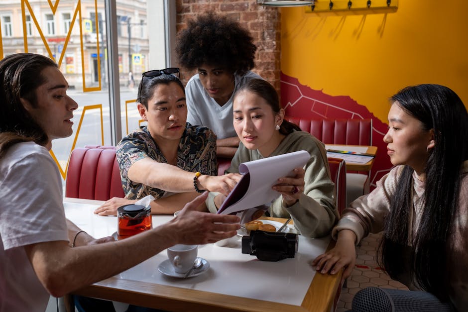 students collaborating on a project with a tablet and notes, in a modern cafe