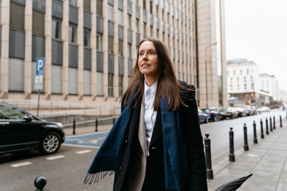 woman in blazer and sneakers walking city street