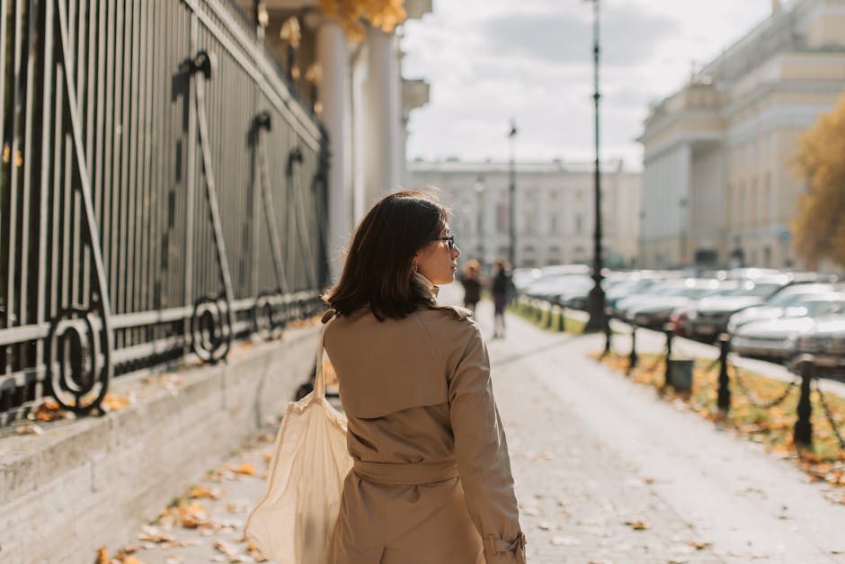woman in trench coat walking city