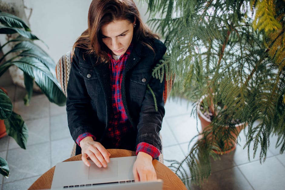 woman using laptop in modern office with green plants