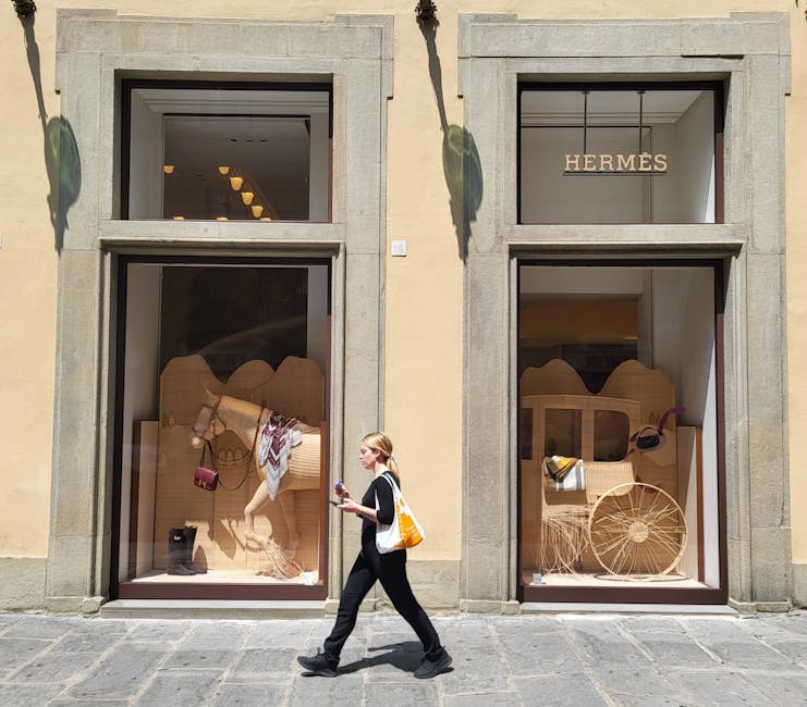 woman walking past store windows with  bags