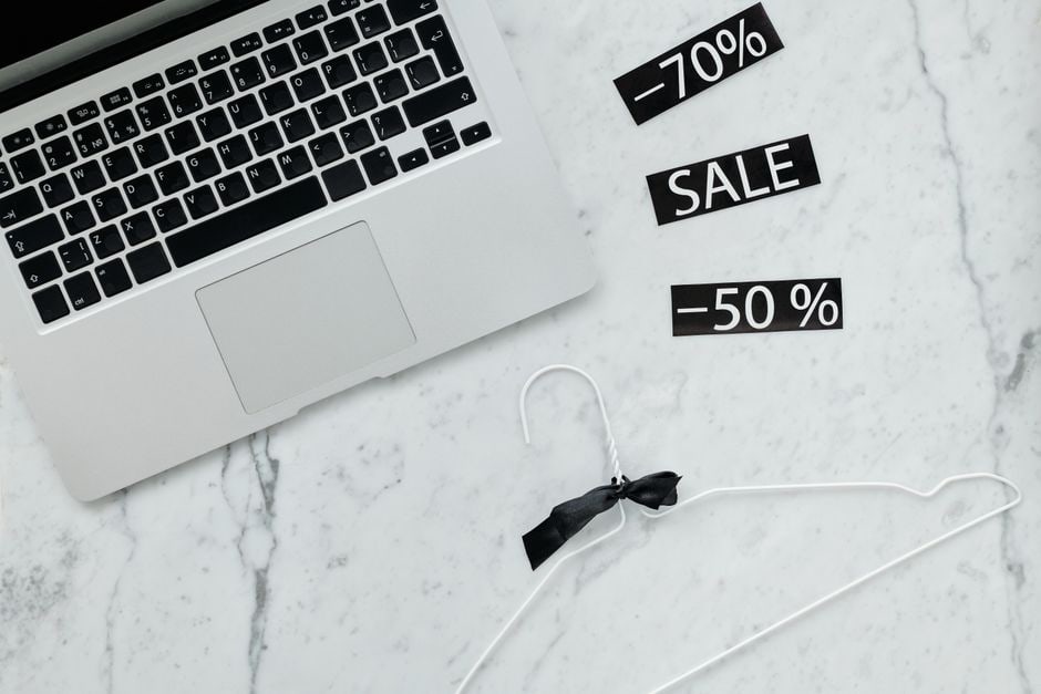 A laptop screen displaying an online store, with a browser extension pop-up showing historical price data and a notification for a price alert.