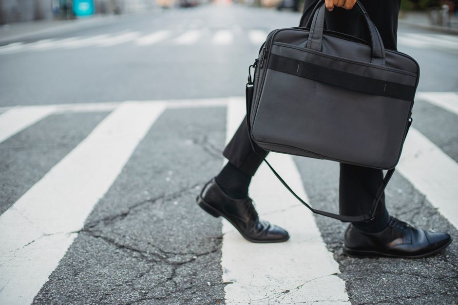 A businessman in a sharp suit walks purposefully through a modern office lobby, his comfortable dress shoes gleaming, reflecting his confident stride.