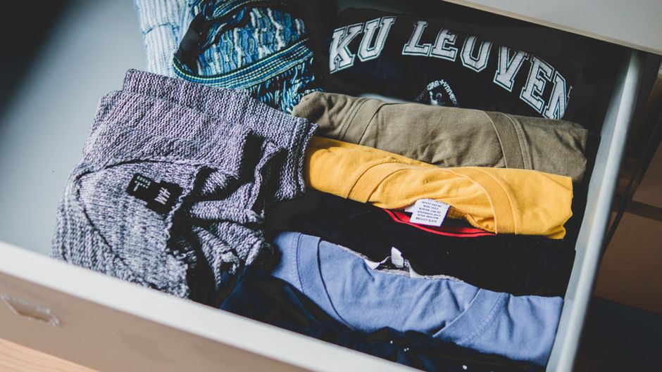 A well-organized capsule wardrobe laid out on a bed, featuring interchangeable neutral tops, trousers, a skirt, and a blazer, ready to create easy workwear outfits for hybrid offices.