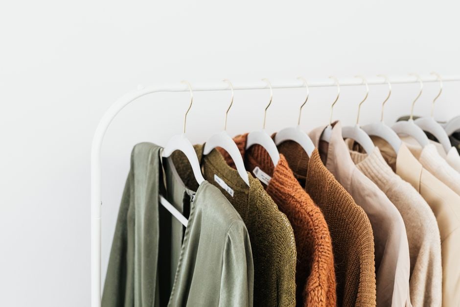A neatly organized minimalist capsule wardrobe with interchangeable sustainable fashion pieces in neutral tones, perfect for versatile outfits.