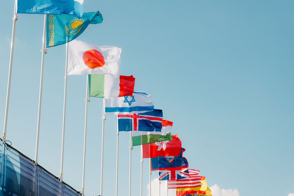 A shopping cart filled with fashion items, featuring small flags representing the US, UK, Germany, and France, symbolizing international deals.