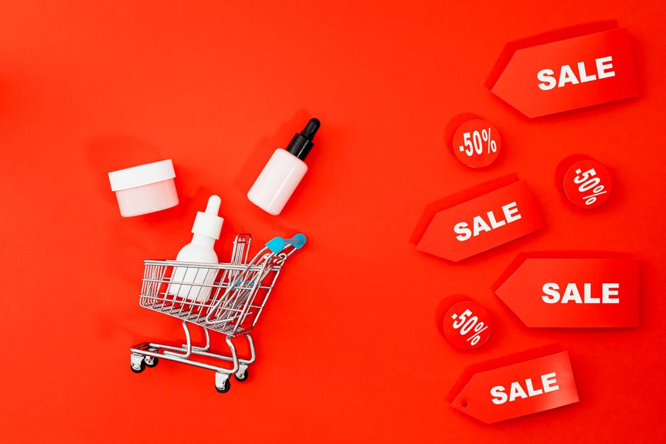 A shopping cart overflowing with items, some clearly unneeded, accompanied by a calculator showing a high total, representing the mistake of buying extra to meet minimum spend.