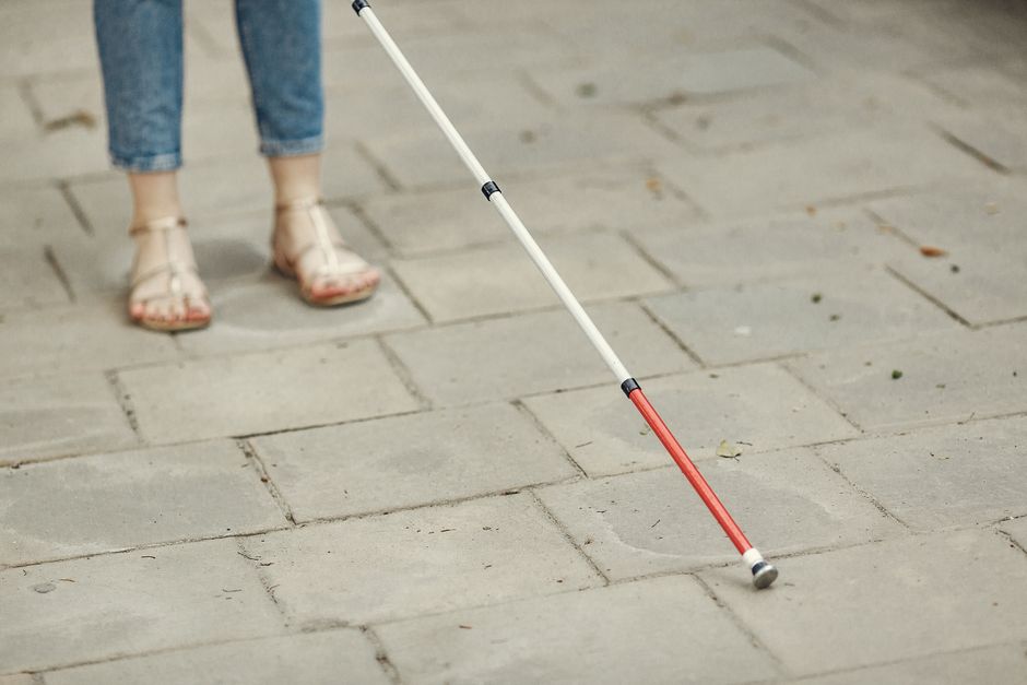 Close-up of a foot in a comfortable, adjustable-strap sandal, showing proper arch support and cushioned sole on a clean urban pavement.