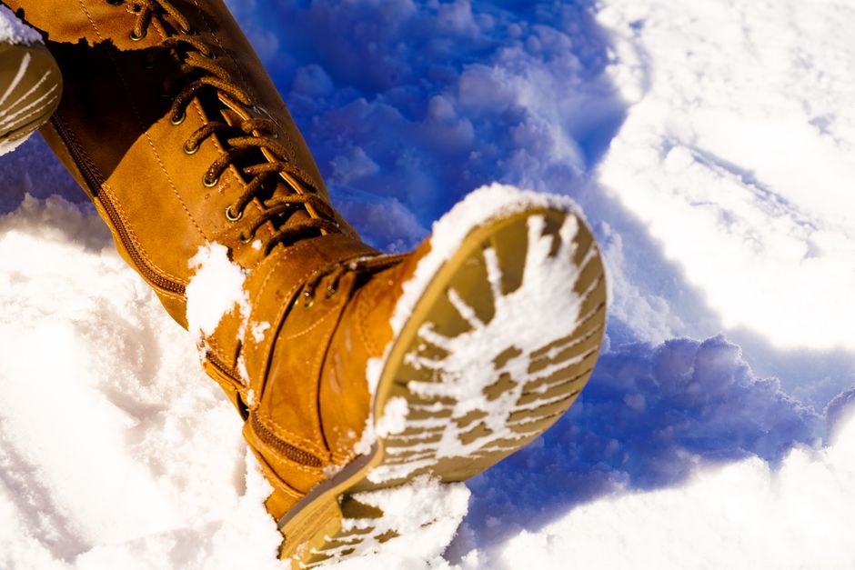 A detailed close-up shot of a winter boot's outsole, highlighting aggressive, multi-directional lugs and siping for ice traction.