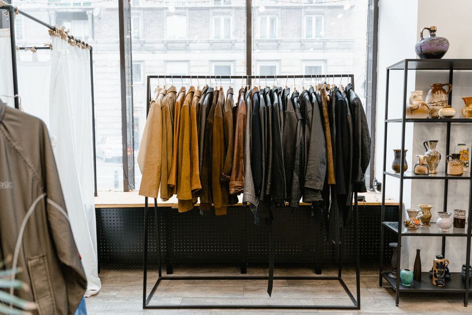 A curated clothing rack displaying a collection of high-quality men's capsule wardrobe essentials, including blazers, shirts, and trousers, made from natural and sustainable fabrics.
