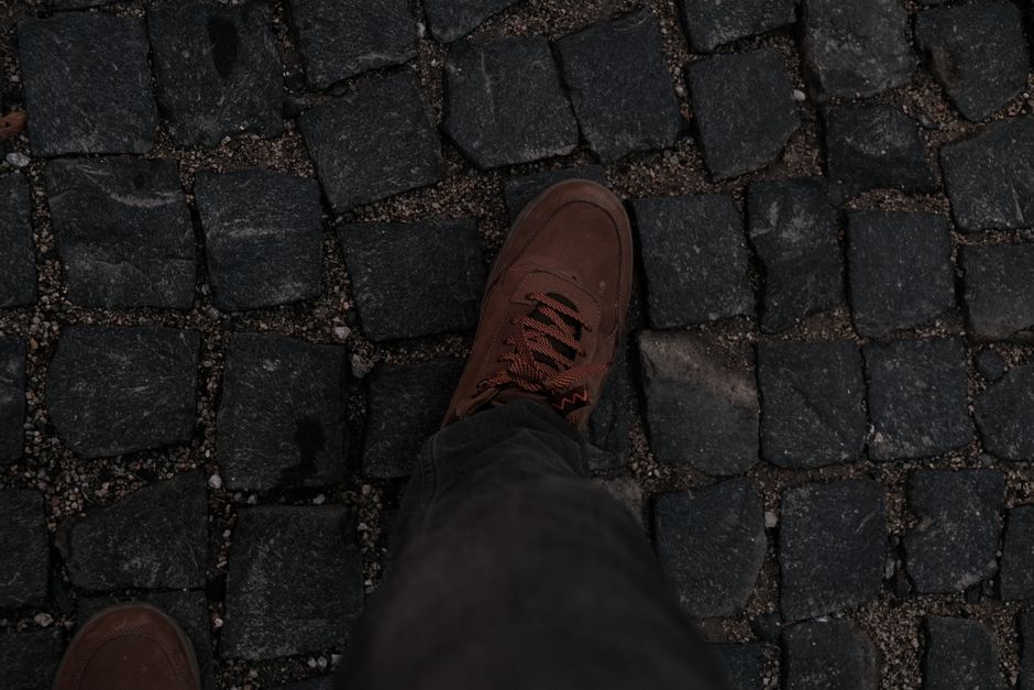 A pair of sturdy, comfortable walking shoes rests on a historic European cobblestone street, ready for travel.
