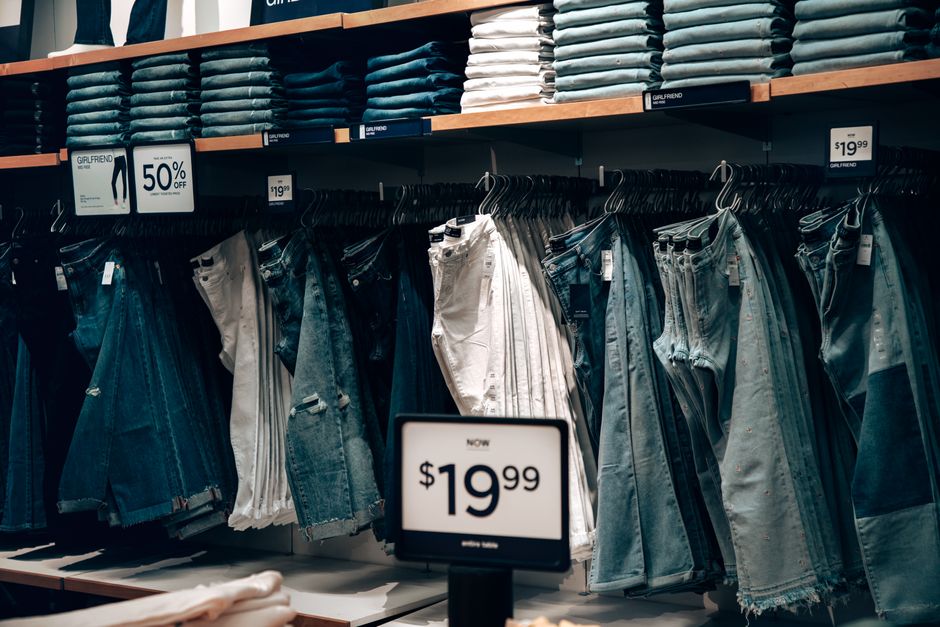 A neatly organized display of various men's jeans in different washes and fits, from dark indigo to light blue, showcasing the diversity available online.