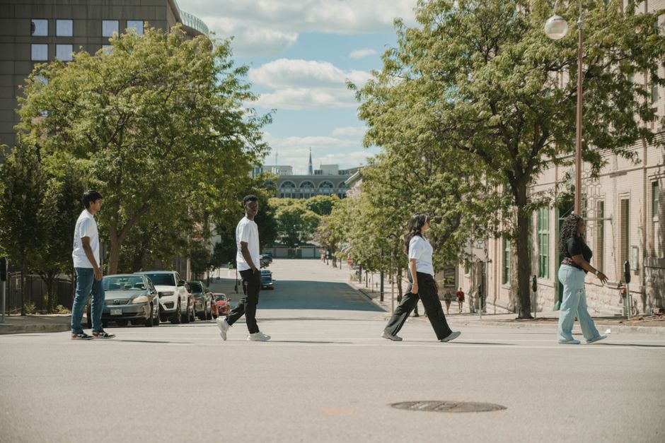 A diverse group of people walking confidently down a bustling city street on a sunny day, showcasing everyday life and the need for sun protection in an urban setting.