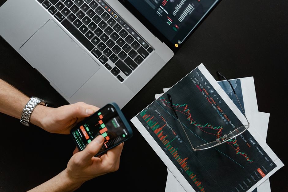 Multiple hands holding smartphones and a laptop, displaying various retail websites and price comparison tools, emphasizing the need for comprehensive price checking.