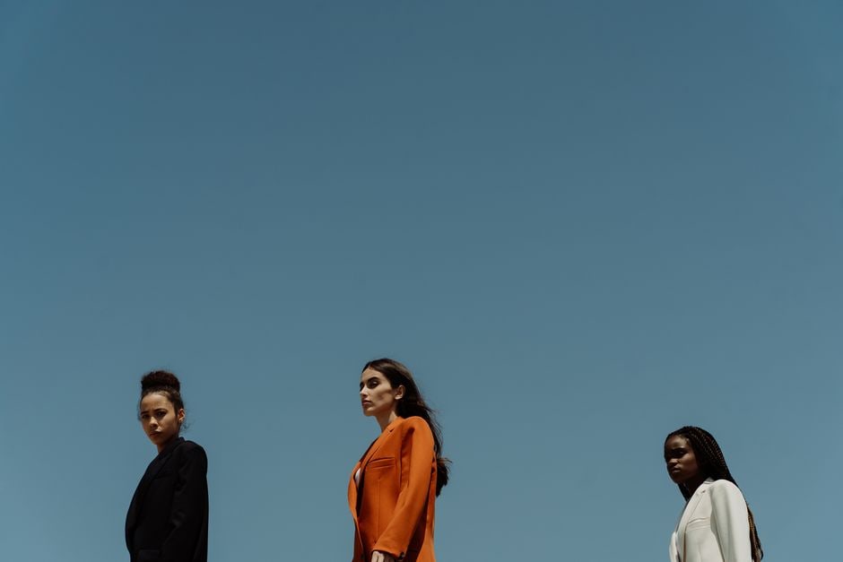 Three diverse women showcasing how to style minimalist basics into elegant, practical outfits for different occasions.