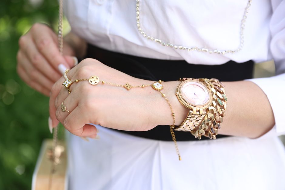 Close-up of a woman adding a delicate necklace to a simple, elegant top, showcasing the power of accessories in women's fashion advice.