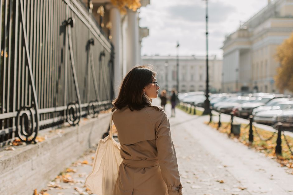 A stylish woman walking confidently in a trench coat through a European city, embodying timeless fashion.