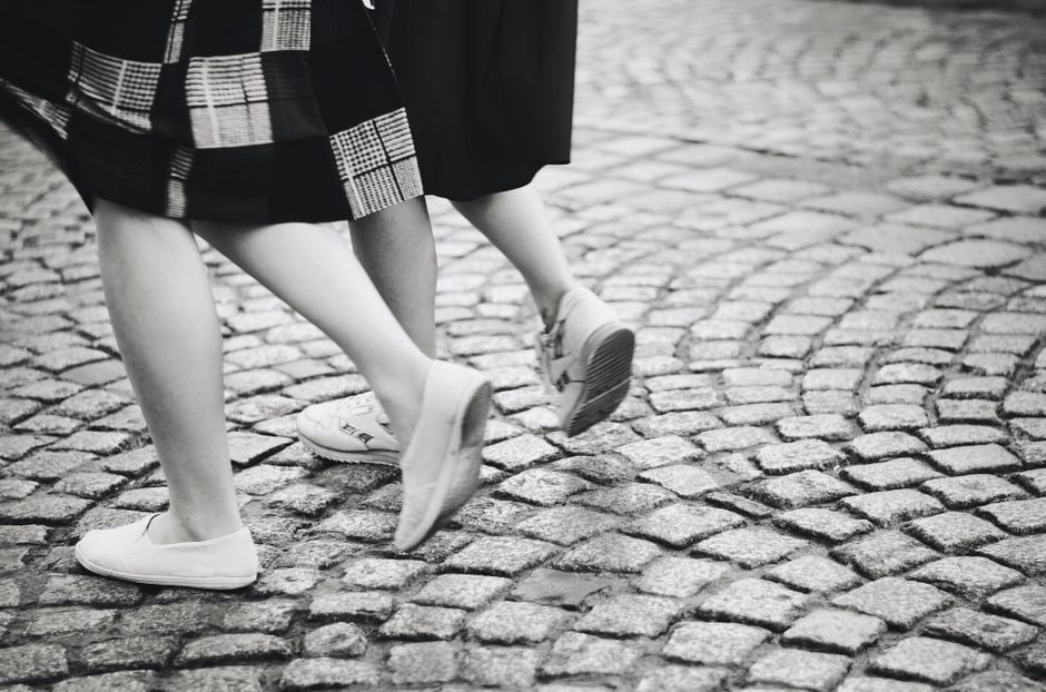 A pair of durable walking shoes designed for support on a historical European cobblestone street.