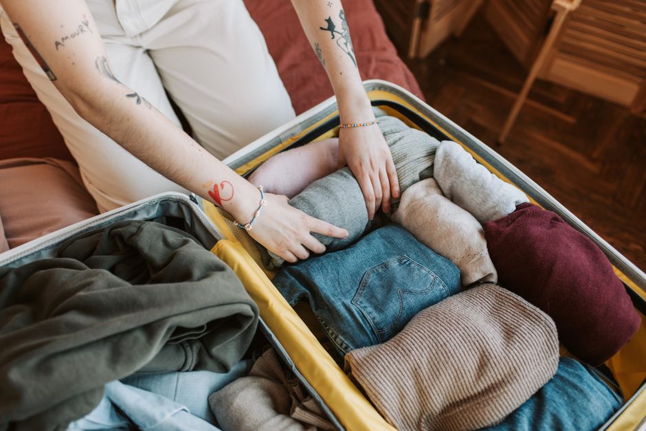 Various clothing items, including a scarf and flat shoes, carefully rolled and packed into a suitcase for efficient travel.