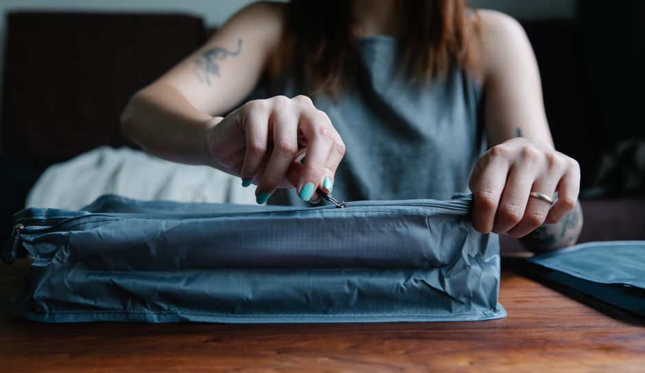 Close-up of hands zipping up a travel laptop bag, highlighting the durable, water-resistant material and strong zippers.