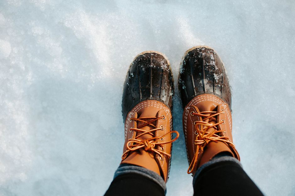A stylish, insulated, and waterproof winter boot standing firmly on a wet, snowy street.