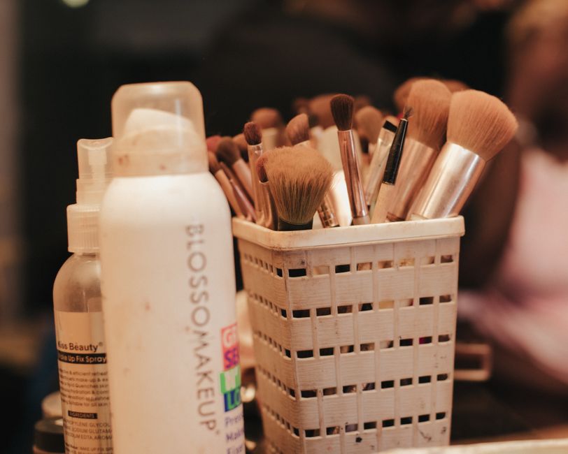 A person with natural-looking makeup spraying a fine mist of setting spray onto their face, demonstrating a step to keep makeup fresh during travel.