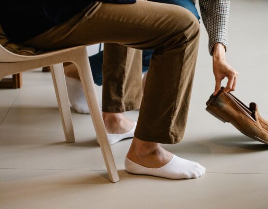 A man in a modern office environment wearing comfortable leather loafers with chinos, looking professional yet relaxed.