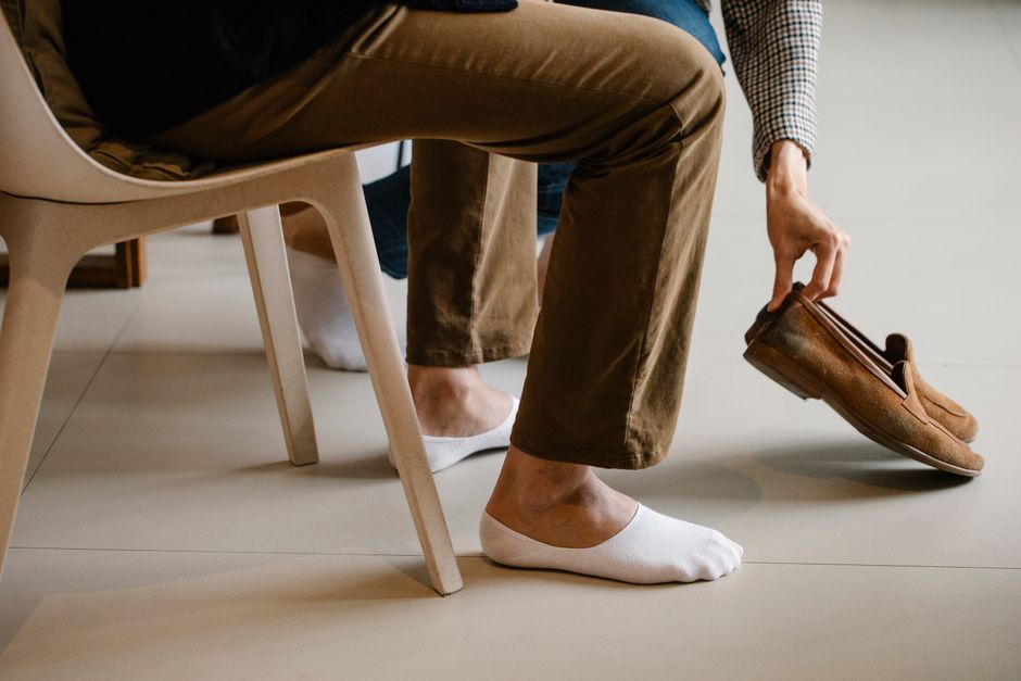A man in a modern office environment wearing comfortable leather loafers with chinos, looking professional yet relaxed.