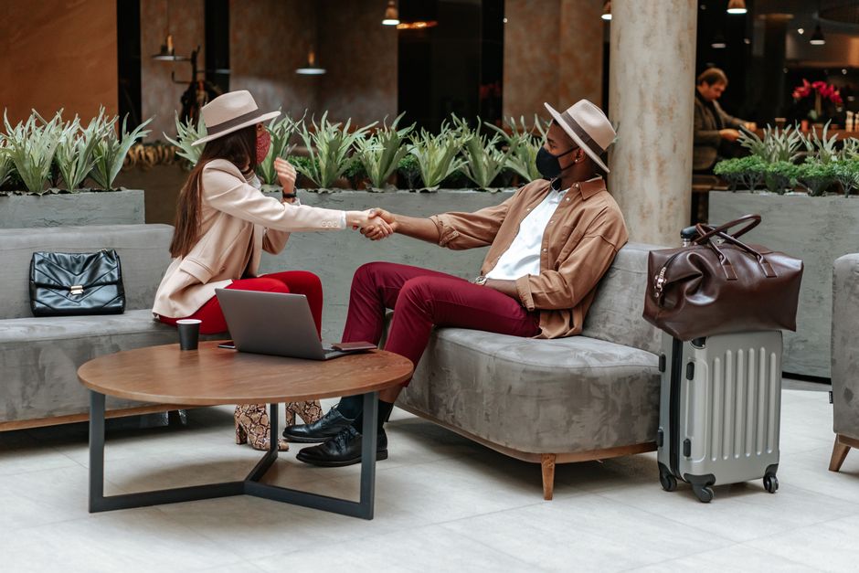 A stylish man in a smart casual outfit, wearing a blazer, chinos, and comfortable sneakers, walking through a modern airport terminal, embodying prepared travel style.