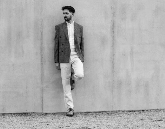 A man in a well-fitted smart casual outfit featuring a blue button-down shirt and chinos, demonstrating versatile sustainable men's fashion basics.
