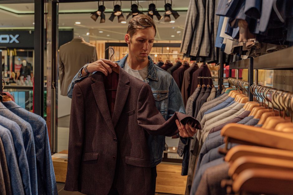 A man dressed in a stylish navy blazer, dark wash jeans, and a crisp white shirt, confidently walking through a European city street, embodying smart casual style for men's outfits for first dates and dinners.