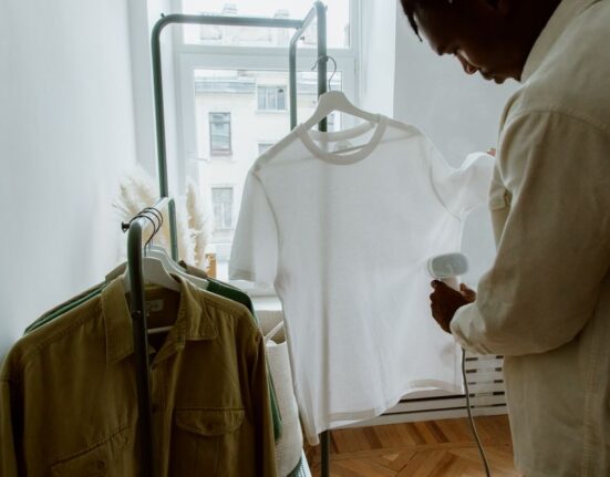 A man stands in front of an open, well-organized wardrobe, contemplating his outfit choices, demonstrating the ease of a capsule collection.