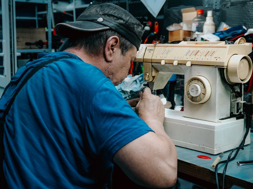 A close-up of a man's hands carefully mending a seam on a shirt, illustrating the importance of repair for sustainable fashion.