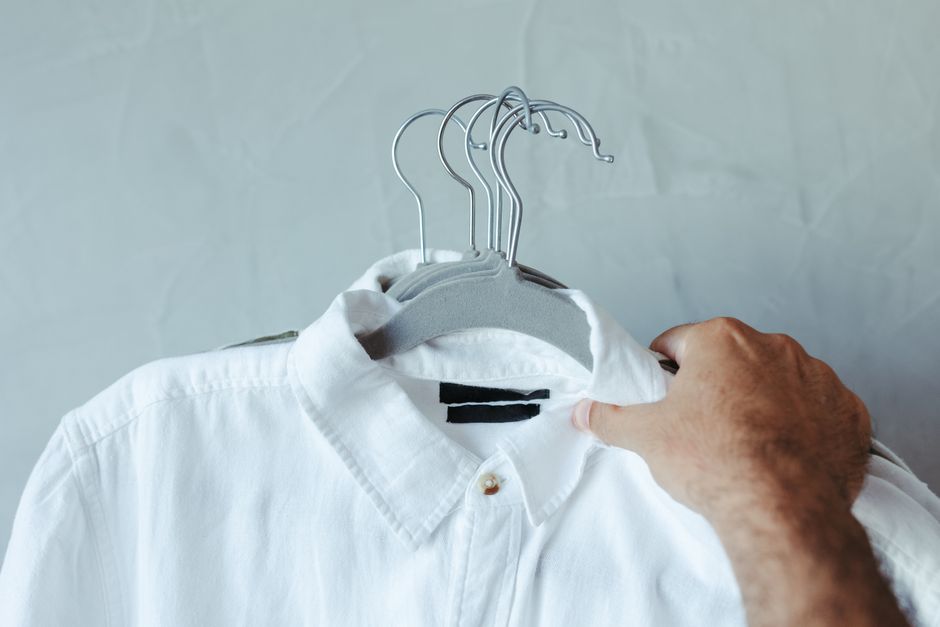 A man thoughtfully choosing a shirt from a well-organized closet, illustrating mindful wardrobe building.
