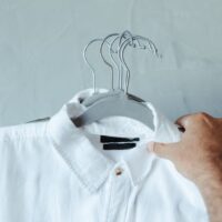 A man in a modern, organized closet carefully selecting a shirt, demonstrating the principle of a minimalist wardrobe.