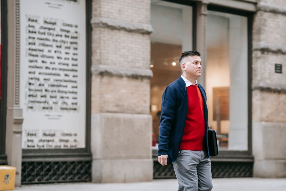 A man in a smart casual outfit – chinos, a polo shirt, and comfortable sneakers – walking confidently down a European city street.