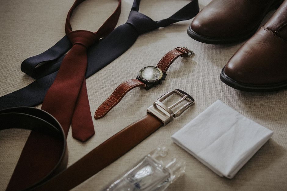 Flat lay of a men's capsule wardrobe, including dark jeans, chinos, button-down shirts, a blazer, and classic shoes, ready for mixing and matching.