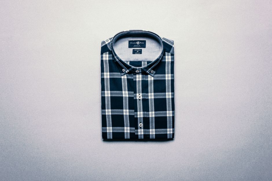 Neatly folded stack of men's clothing essentials like t-shirts, sweaters, and jeans, emphasizing quality.