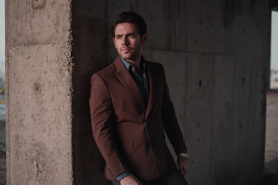 A well-dressed man showcasing a smart casual outfit consisting of a navy unstructured blazer, light blue Oxford shirt, tailored beige chinos, and loafers.