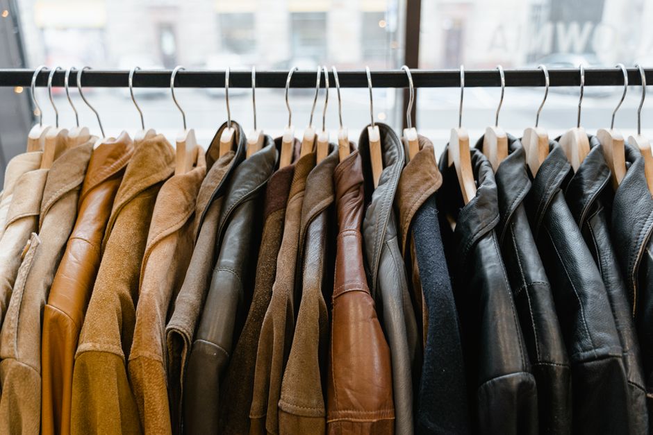 A neatly organized men's smart casual capsule wardrobe featuring blazers, shirts, chinos, and sweaters on a minimalist clothing rack.