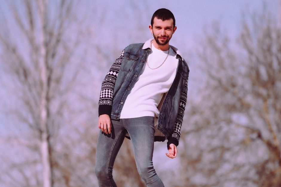 A close-up of a man's torso showcasing multiple layers: a base layer, a fine-knit sweater, and a blazer, ready for an urban winter.
