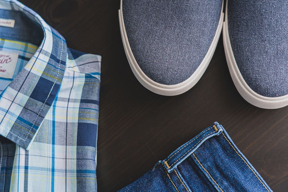 A flat lay showing essential men's summer outfits: a white linen shirt, tailored navy shorts, a striped polo, espadrilles, and sunglasses, highlighting versatile pieces for hot weather.