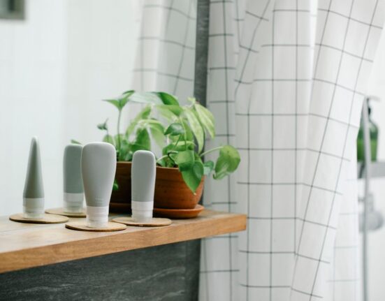A clean, white bathroom shelf displaying a few essential, affordable skincare products like cleanser, moisturizer, and a simple serum, representing a minimalist routine.