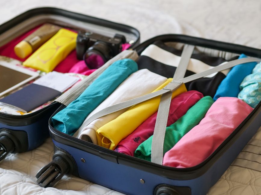 An open travel backpack revealing a dedicated padded laptop compartment and neatly organized clothing, ready for a combined business and leisure trip.