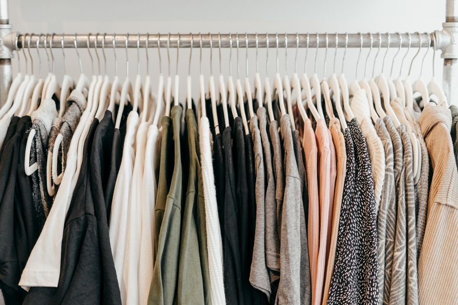 A perfectly organized capsule wardrobe displayed on hangers and shelves, featuring neutral-colored, versatile clothing items.