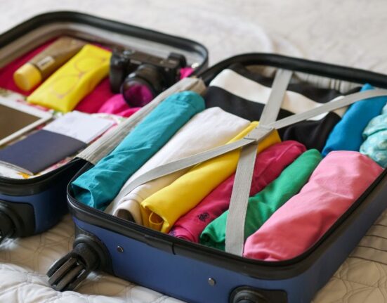 An open travel backpack revealing neatly organized compartments for laptop, tablet, documents, and small essentials, illustrating efficient packing.