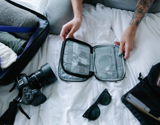 An open travel backpack revealing neatly organized compartments for laptop, phone, power bank, and other small essentials, emphasizing efficient packing.