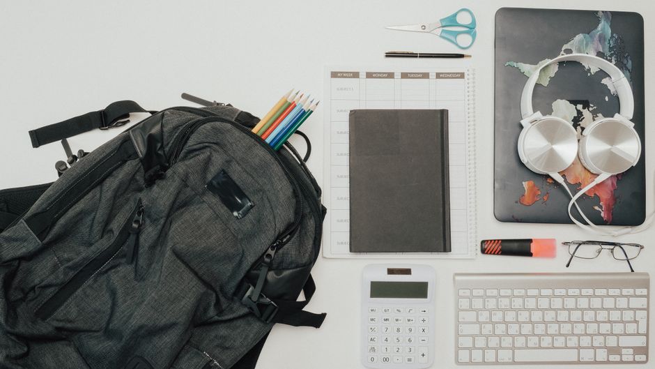 An open travel backpack showcasing organized compartments for a laptop, tablet, water bottle, and various travel essentials, ready for a trip or work.